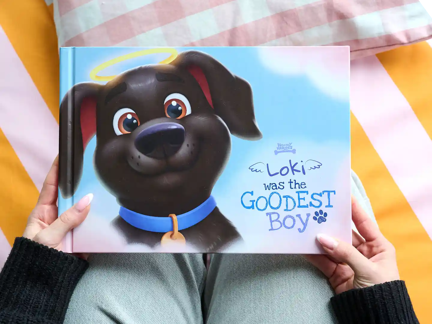 Personalized dog memorial book titled 'Loki Was the Goodest Boy' by Hooray Heroes, held by a pet owner.